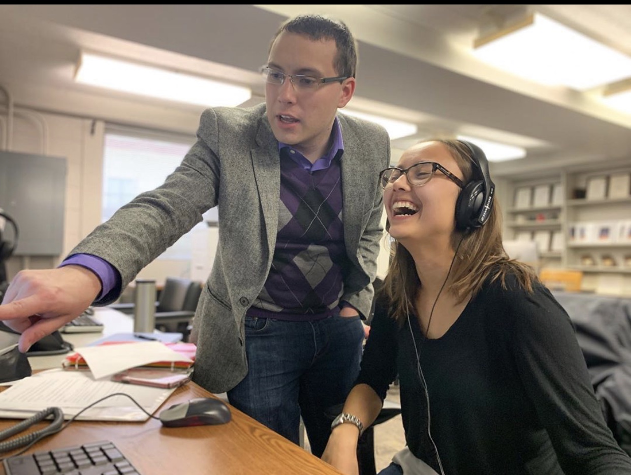A professor helps a student working at a computer.